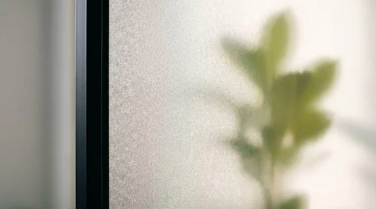 Gros plan d'un panneau de verre dépoli d'une porte intérieure avec lumière naturelle diffusée à travers la surface texturée